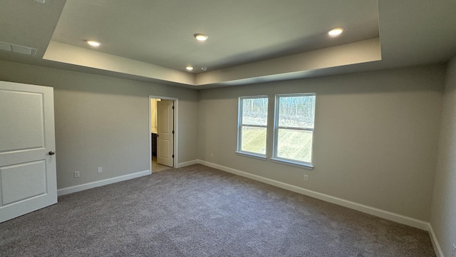 carpeted spare room featuring a tray ceiling