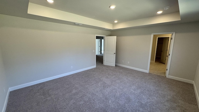 unfurnished bedroom with a raised ceiling and carpet flooring