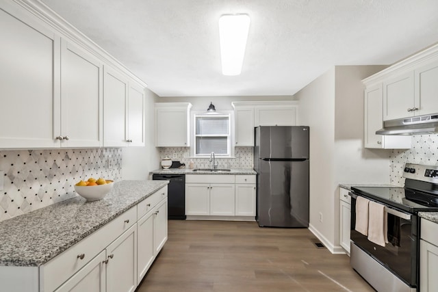 kitchen with sink, hardwood / wood-style flooring, white cabinetry, light stone counters, and stainless steel appliances