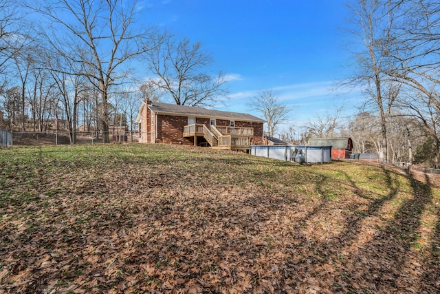 rear view of house featuring a swimming pool side deck and a lawn