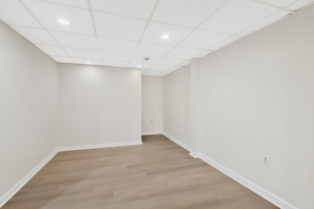 spare room featuring a drop ceiling and light hardwood / wood-style flooring