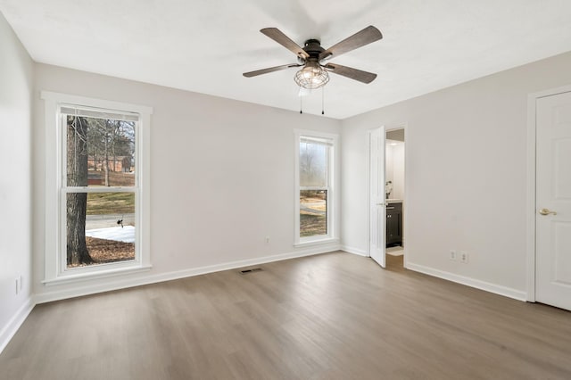 empty room with ceiling fan, hardwood / wood-style flooring, and a wealth of natural light