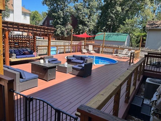 deck featuring a fenced in pool, central air condition unit, and outdoor lounge area