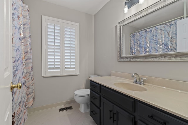 bathroom with toilet, vanity, and tile patterned flooring