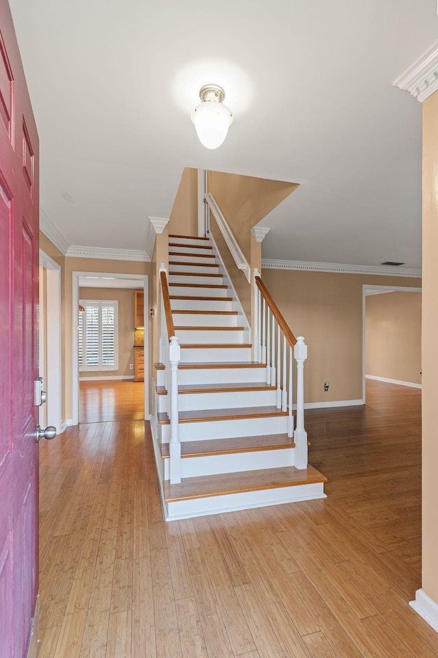 stairway featuring wood-type flooring and crown molding