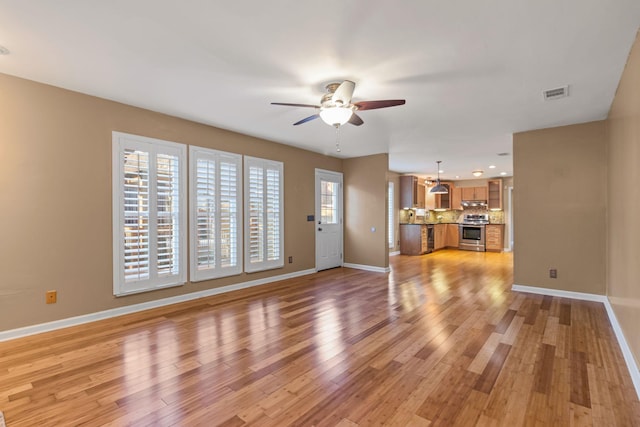 unfurnished living room featuring ceiling fan, light wood-type flooring, and a healthy amount of sunlight