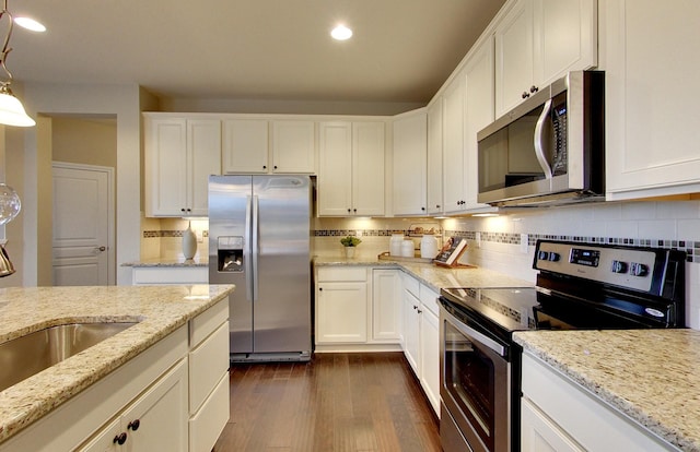 kitchen with light stone counters, stainless steel appliances, and white cabinetry