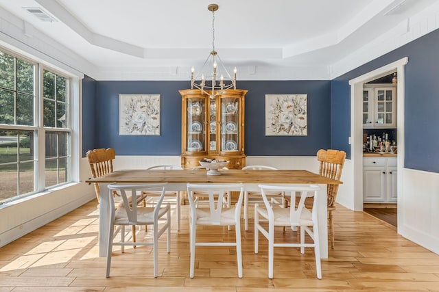 dining room with light hardwood / wood-style floors, a tray ceiling, and a chandelier