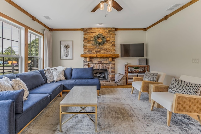 living room featuring ceiling fan, hardwood / wood-style flooring, ornamental molding, and a stone fireplace