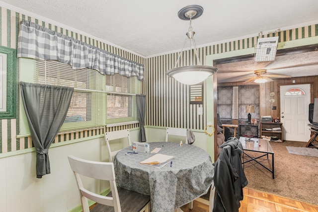 dining area featuring parquet flooring, wood walls, a textured ceiling, ornamental molding, and ceiling fan