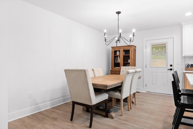 dining space featuring baseboards, an inviting chandelier, and light wood finished floors