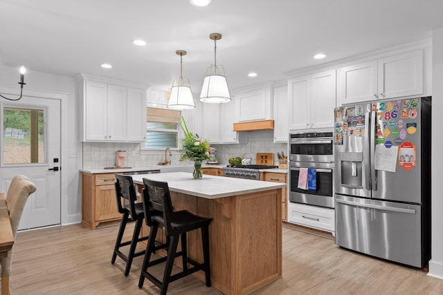 kitchen featuring a kitchen island, stainless steel appliances, decorative backsplash, light countertops, and light wood-type flooring