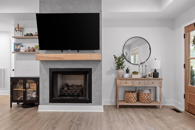 unfurnished living room featuring visible vents, baseboards, wood finished floors, and a fireplace