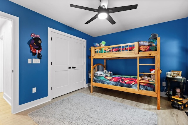 bedroom featuring ceiling fan, a closet, baseboards, and wood finished floors