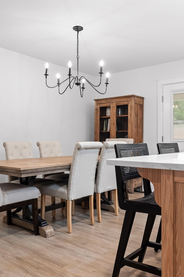 dining area with light wood-style floors and a notable chandelier