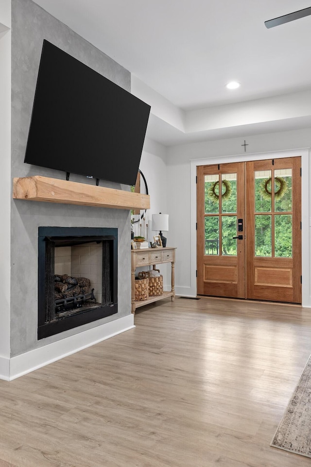 unfurnished living room featuring a fireplace, wood finished floors, baseboards, and french doors