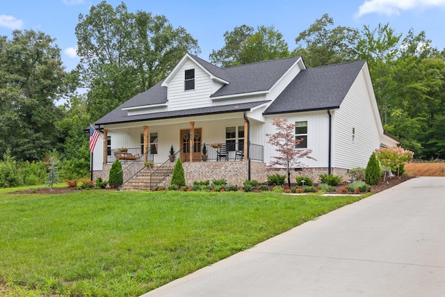 view of front of home with roof with shingles, a porch, and a front lawn