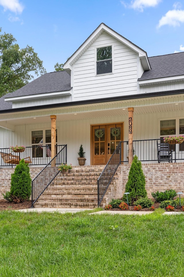 view of front of home featuring a front lawn, a porch, stairs, and a shingled roof