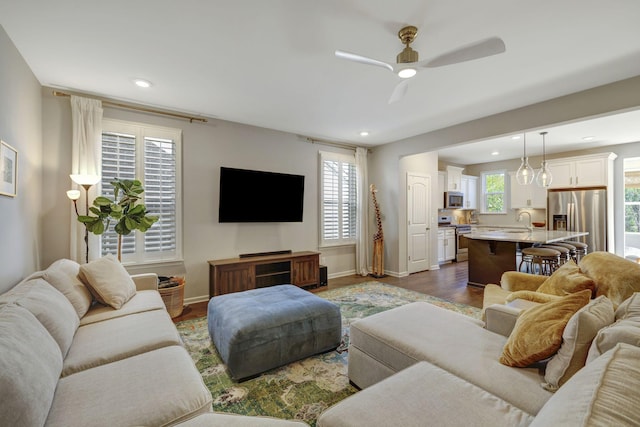 living room with dark wood-type flooring, ceiling fan, and sink