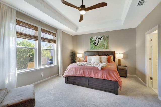 bedroom with ceiling fan, light carpet, and a tray ceiling