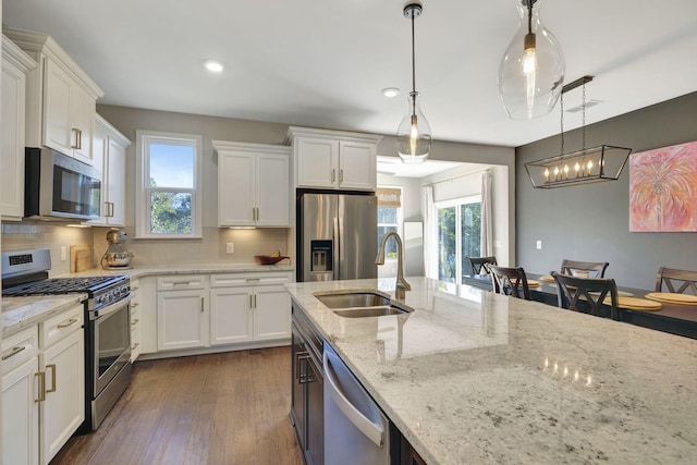 kitchen featuring hanging light fixtures, appliances with stainless steel finishes, and white cabinetry