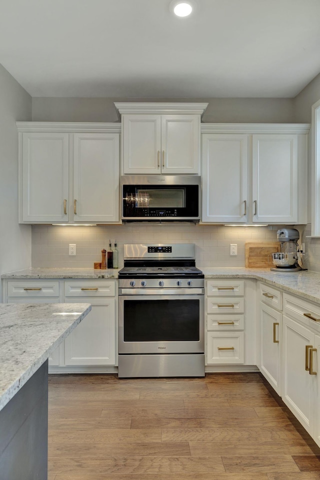 kitchen featuring stainless steel appliances, light hardwood / wood-style floors, white cabinetry, and light stone counters