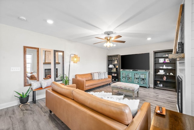 living room featuring a large fireplace, hardwood / wood-style flooring, and ceiling fan