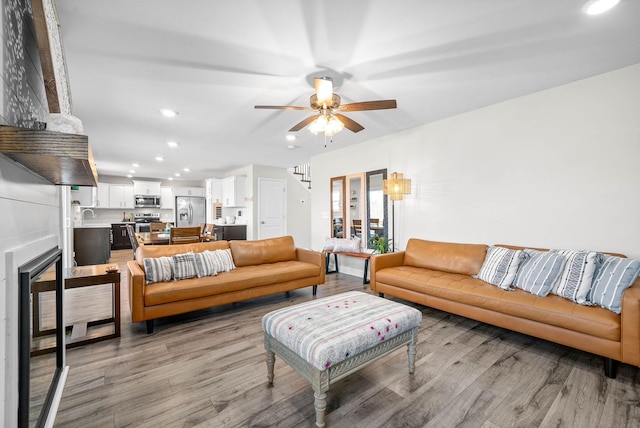 living room with light wood-type flooring, ceiling fan, wine cooler, and sink