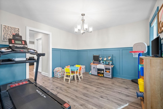 exercise room featuring a chandelier and light hardwood / wood-style flooring