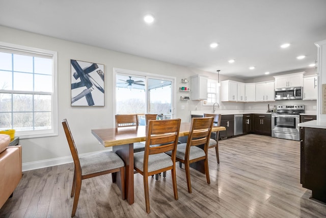 dining area with sink, light hardwood / wood-style floors, a healthy amount of sunlight, and ceiling fan