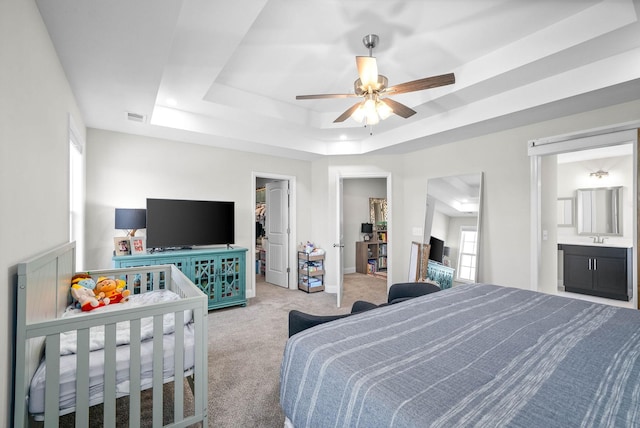 bedroom featuring ceiling fan, a tray ceiling, a spacious closet, connected bathroom, and a closet