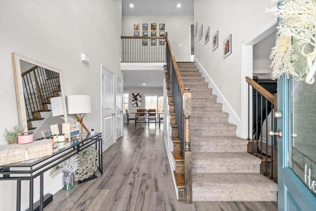 staircase with hardwood / wood-style flooring and a towering ceiling