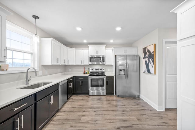 kitchen featuring sink, stainless steel appliances, white cabinets, and decorative light fixtures