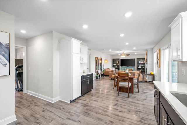 kitchen with light hardwood / wood-style floors, white cabinets, and ceiling fan