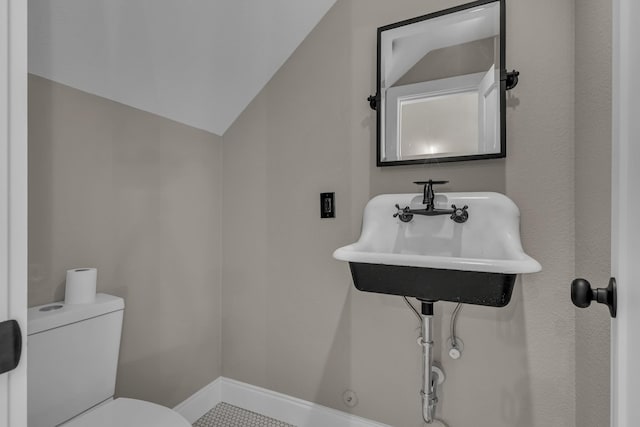 bathroom with toilet, vaulted ceiling, sink, and tile patterned flooring