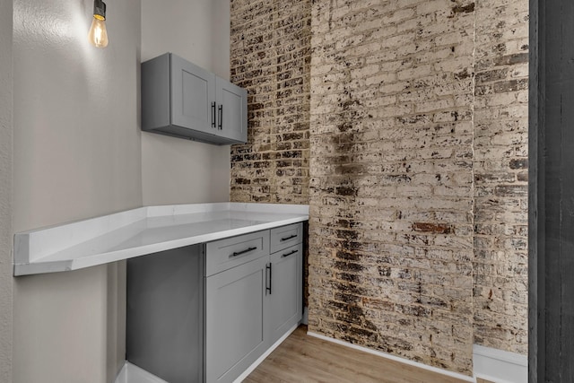 kitchen featuring brick wall, gray cabinets, and light wood-type flooring