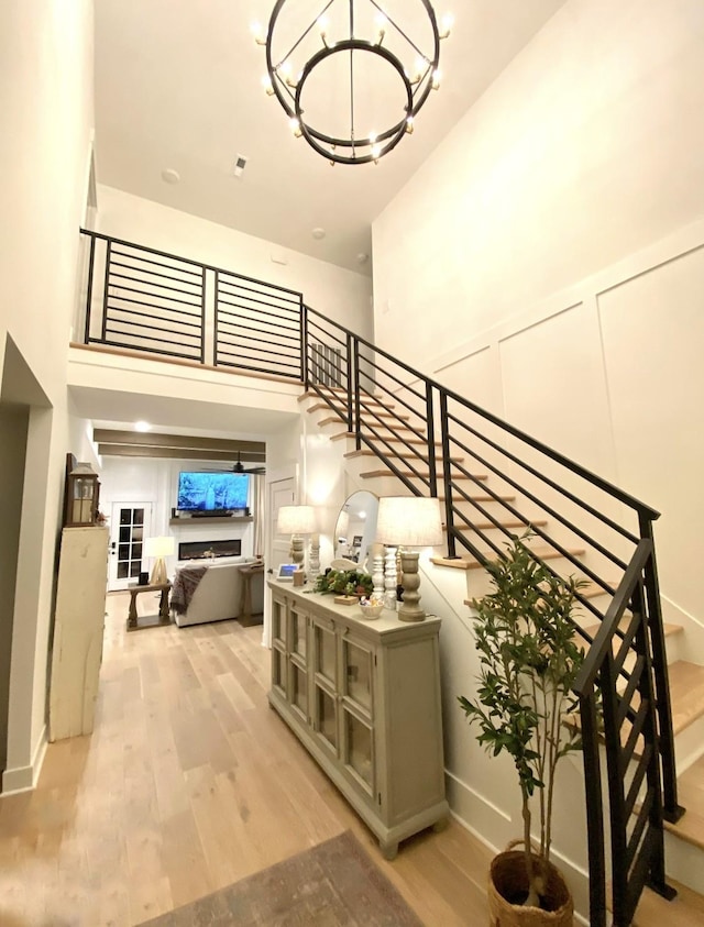 staircase with hardwood / wood-style flooring, a towering ceiling, and a chandelier