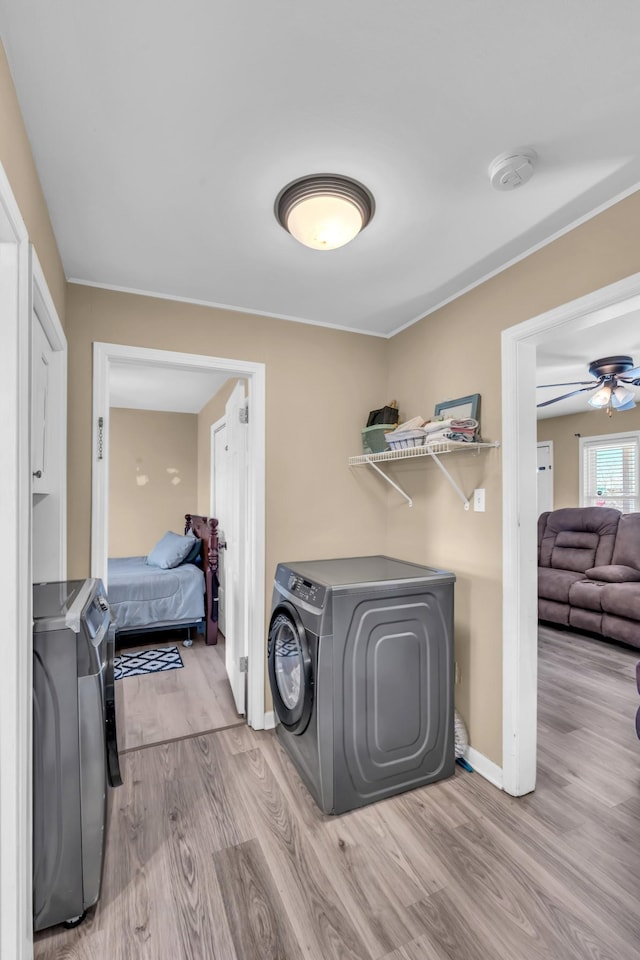 laundry room featuring ceiling fan, washing machine and clothes dryer, and light hardwood / wood-style flooring