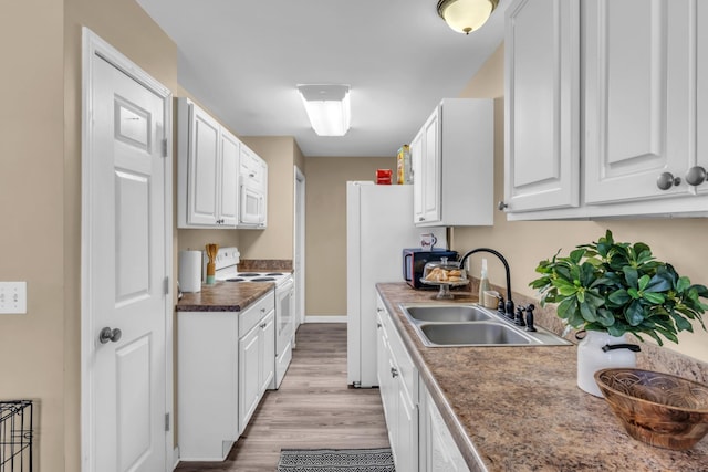 kitchen with white cabinetry, sink, white appliances, and light hardwood / wood-style floors