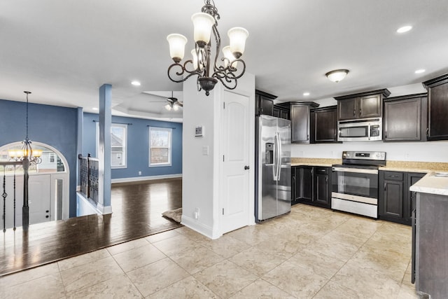 kitchen featuring hanging light fixtures, dark brown cabinets, stainless steel appliances, light tile patterned flooring, and ceiling fan with notable chandelier