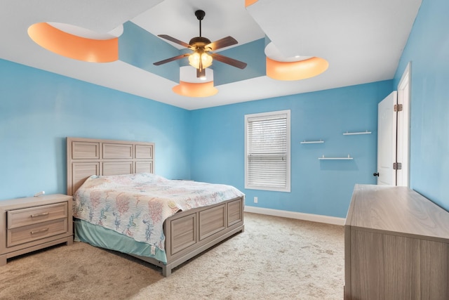 carpeted bedroom featuring ceiling fan and a tray ceiling