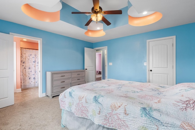 carpeted bedroom featuring ceiling fan and a tray ceiling