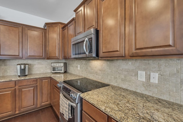 kitchen with light stone countertops, appliances with stainless steel finishes, dark wood-type flooring, and decorative backsplash