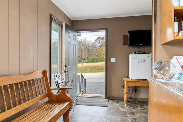 doorway featuring wooden walls and ornamental molding