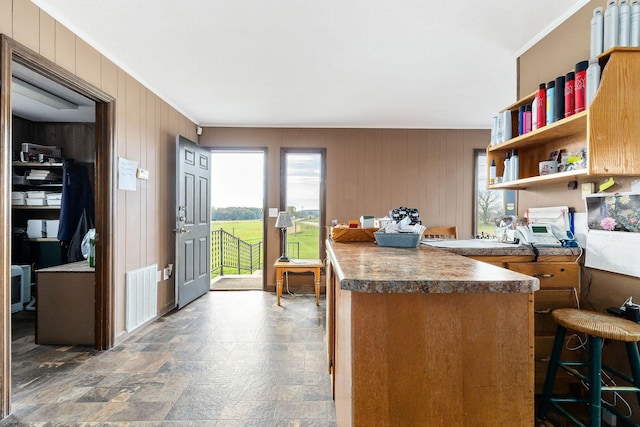 kitchen featuring a kitchen bar, kitchen peninsula, and wooden walls