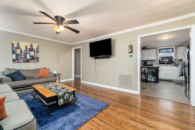 living room with ceiling fan, wood-type flooring, and crown molding