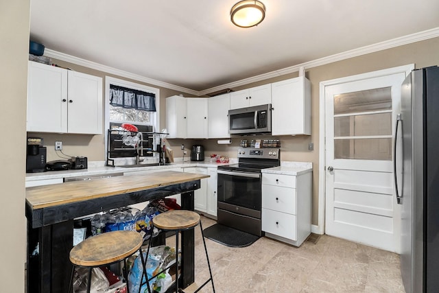 kitchen featuring white cabinets, appliances with stainless steel finishes, and crown molding