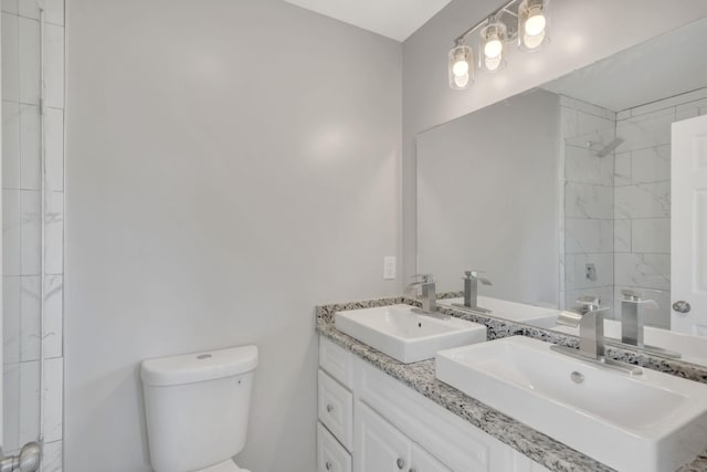 bathroom with toilet, tiled shower, and vanity