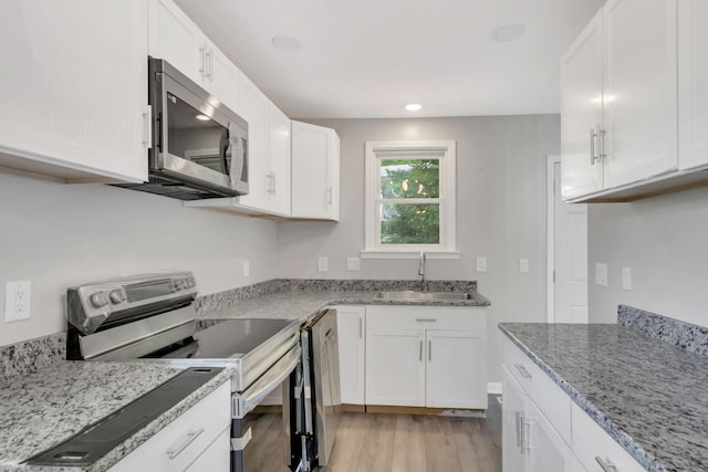 kitchen with white cabinets, light stone countertops, sink, and stainless steel appliances