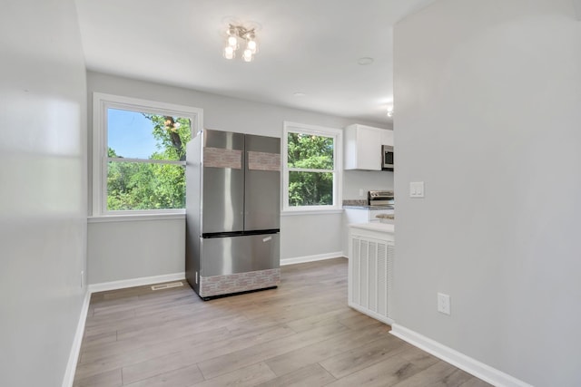 kitchen featuring plenty of natural light, white cabinetry, light hardwood / wood-style flooring, and stainless steel appliances